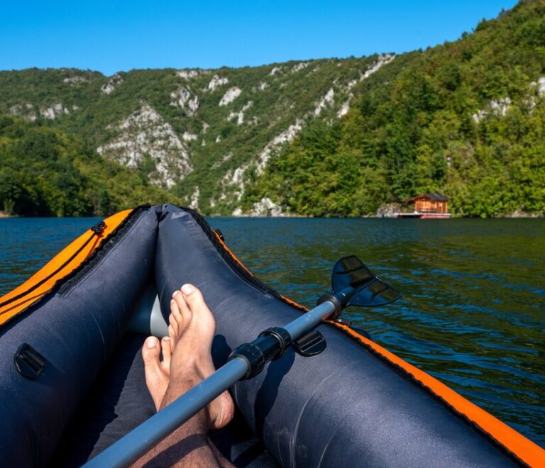 man-kayaking-lake-surrounded-by-hills-covered-greens_181624-49279